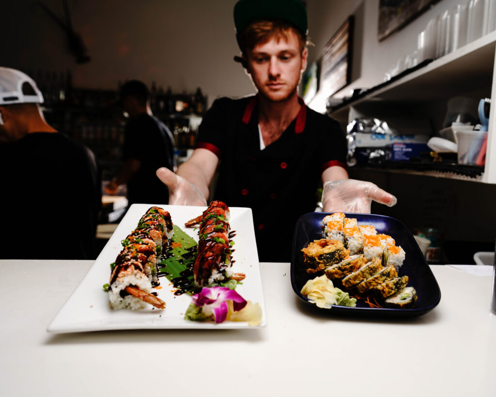 Blu Sushi employee presenting sushi rolls in Fort Myers, Florida
